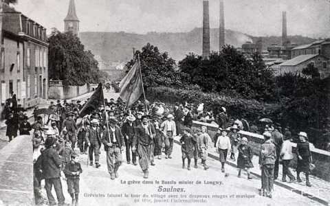 Grévistes tenant des drapeaux faisant le tour du village (Saulnes)